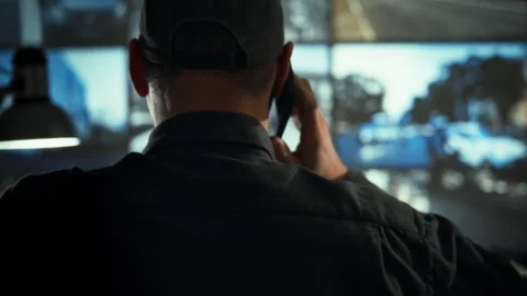 In a monitoring service control room an employee speaks on a phone while sca Stock Footage 334546048
