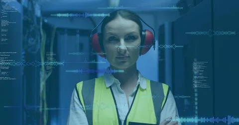 Monitoring tech in high-vis vest red earmuffs scanning racks in blue LED data Stock Photos