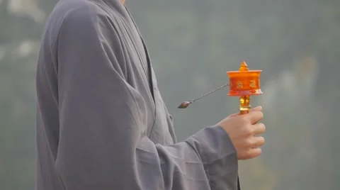 Monk in grey robe prays with praying wheel,Kushinagar,India Video stock 66684104