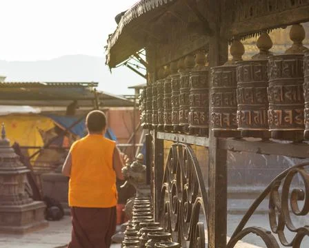 Monk praying at prayer wheels spinning them for good fortune. Stock Photos