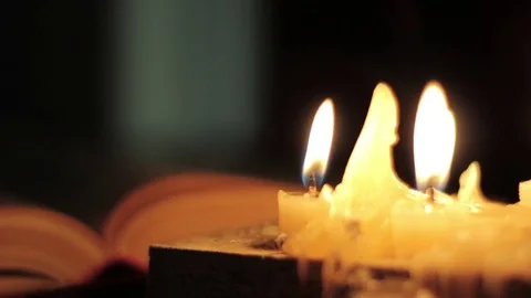 Monk reading and touching a yellow pages of old book. Close-up candle light Stock Footage 74616258