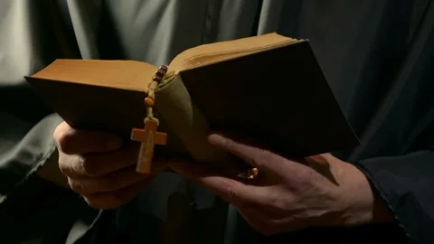 Monk reads from open prayer book and gestures during devotion Stock Footage 342510972