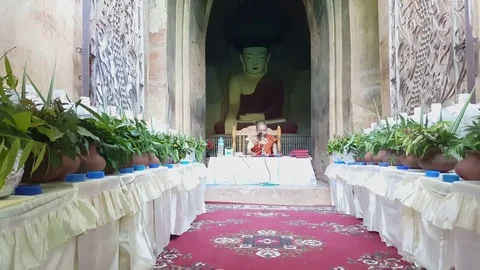 Monk recites prayer into microphone under big seated Buddha statue, Bagan Vídeos de archivo 78845510