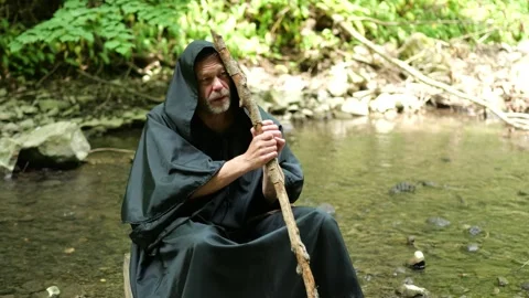 Monk Resting by a Forest Stream with a Staff Stock Footage 336784245