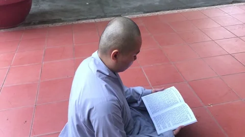 A monk sits on the ground and reads scripture book Stock Footage 142675136