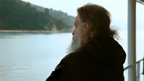 The monk stands on the deck of the ferry and looks at the coast of Mount Athos. Stock Footage 252747436