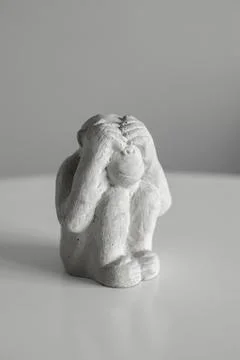 A monkey figurine that sits and closes its eyes with its hands. I don't see Stock Photos