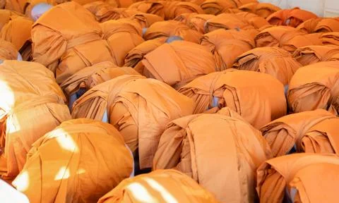 Monks bow forward together in a packed indoor ritual. Orange robes cover th.. 스톡 사진