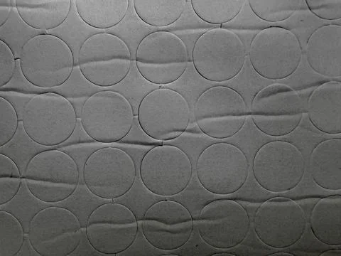 Monochromatic geometric pattern of circular paper stickers on textured gray c 库存照片