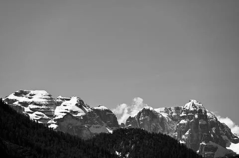 Monochrome Alpine Range with Snow-Capped Peaks and Forest Slopes Stock Photos