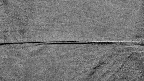 Monochrome denim texture with a sharp horizontal fold crease and diagonal wea Stock Photos