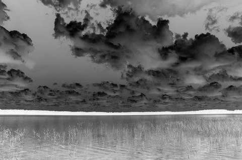 Monochrome dramatic clouds over calm lake Foto stock