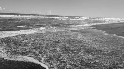 Monochrome high angle view captures glistening ocean water sheet washing ov.. Stock Photos