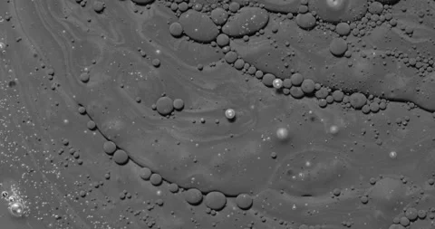Monochrome liquid bubbles form curved trails over a swirling surface Stock Footage 344968433