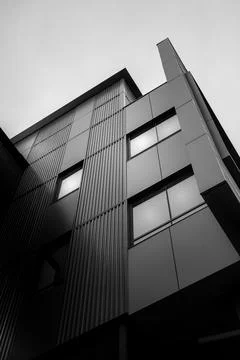 Monochrome low-angle upward perspective of a modern dark metal building facade Stock Photos