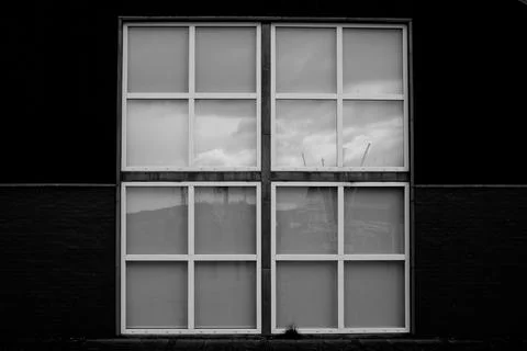 Monochrome shot of treeslarge rectangular sash windows on a black wall 写真素材