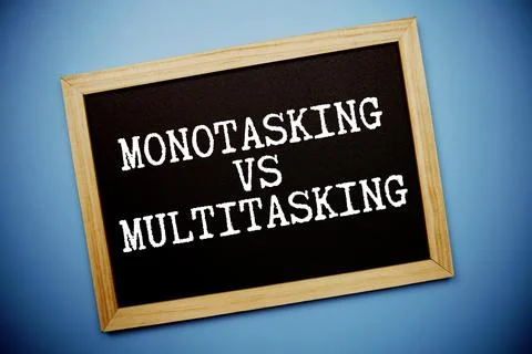Monotasking Vs Multitasking text written on chalkboard flat lay on blue bac.. Stock Photos