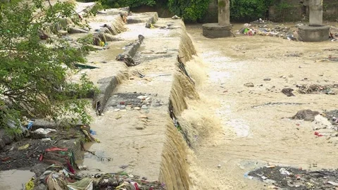 Monsoon flood water flowing over concrete canal steps a view of high, muddy Vídeo Stock 342586672