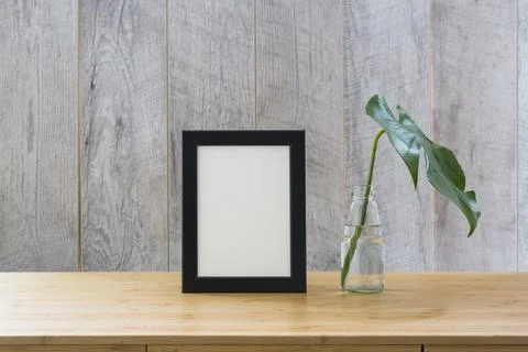 Monstera leaf glass bottle frame wooden table Stock Photos