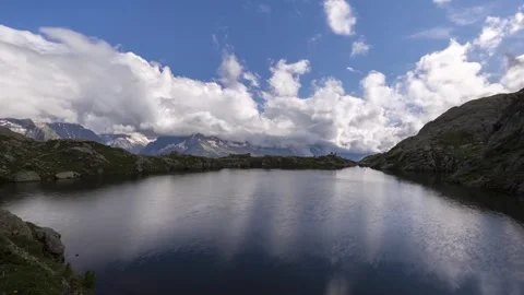 Mont blanc alpine lake reflection cloud drift across blue sky Stock Footage 340861554