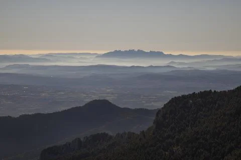 Montserrat mountain range appearing through layers of atmospheric fog Stock Photos
