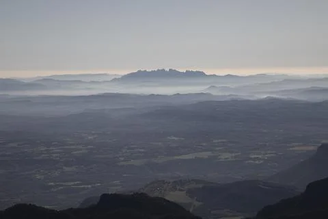 Montserrat mountain range appearing through distant mist Stock Photos