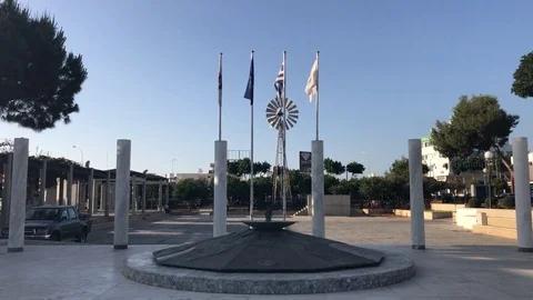 Monument with Flags waving vs Windmill at the background in Paralimni Stock Footage 91568492