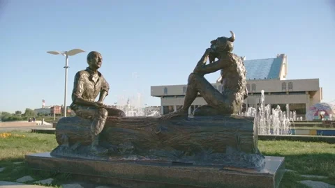 Monument of man with demon sitting on tree trunk in park Stock Footage 219471438