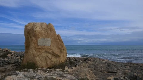 Monument on rocks at the ocean on a cloudy winters day Stock Footage 94489457