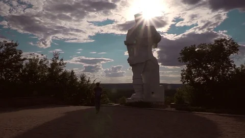 Monument statue against square, trees, sun and sky with clouds. Monument to Stock Footage 92165090