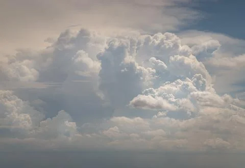 A monumental, billowing cloud rises like a celestial fortress, its crests s.. Stock Photos