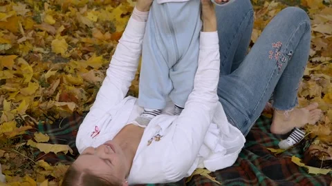 Mood plays with a small cute child lies on the ground covered with leaves. Stock Footage 130747228