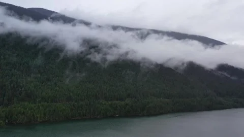 Moody Aerial View of Low Clouds Over Mountains and Forest Lake in British 스톡 동영상 334179792
