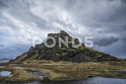 Moody and dramatic scene of a small hill along the Southern shore of Iceland Stock Photos