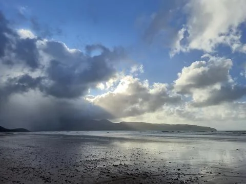 Moody beach shoreline under dramatic clouds at dusk Stock Photos