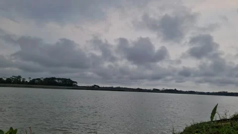 Moody blue overcast sky over calm flowing river in rural area Video stock 332503519
