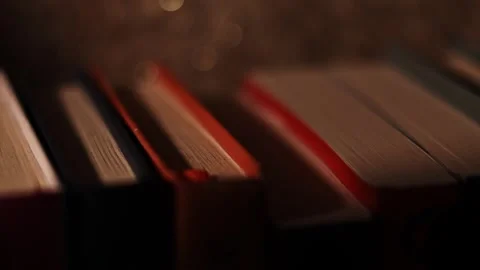 Moody bookshelf close-up with soft backlight and shallow depth of field Stock Footage 339773668