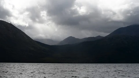 Moody clouds moving over mountains behind a lake Video stock 95824324