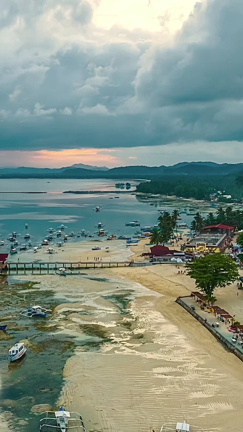 Moody Cloudy Sky Over Low Tide Beach With Moored Boats and Coastal Town at Stock Footage 348268644