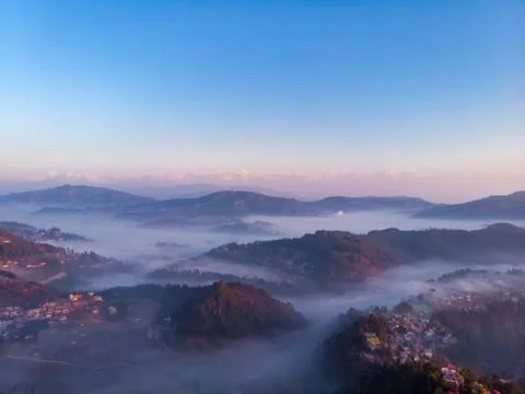 Moody Dramatic view of mountains covered in fog during sunrise with Great Him Stock Photos