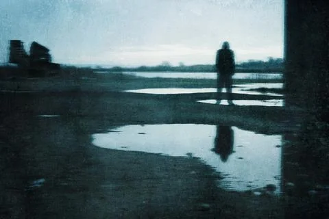 A moody figure, reflected in a puddle. Standing under a bridge Stock Photos