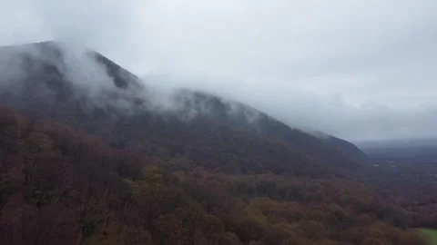 A moody landscape of dense deciduous forest hills partially covered by low-.. Stock Footage 332004494