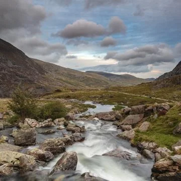 Moody landscape image of river flowing down mountain range near Llyn Ogwen an Stock Photos
