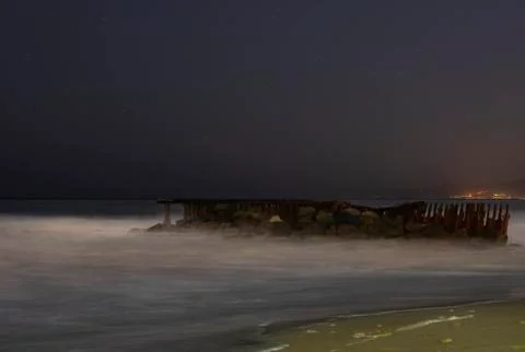 Moody long exposure of a collapsed structure on the surf Stock Photos