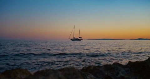 Moody Mallorca Seashore at Sunset with Waves, Rocks and a Yacht in Slow Motion Stock Footage 343589610
