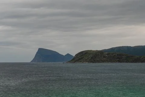 Moody seascape with angular mountain on background. Cloudy weather. Stock Photos