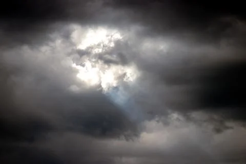 Moody sky with dramatic clouds, subtle rays of light peeking through darkness Stock Photos