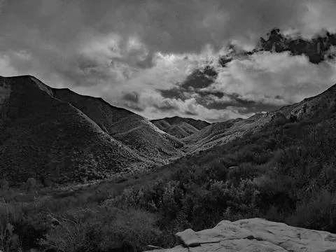 Moody storm clouds hover over rolling coastal range hills and rugged terrain Stock Photos