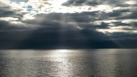 Moody time-lapse of epic sun rays over water as storm approaches darkening Stock Footage 238969373