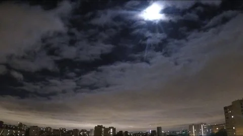 Moon among the clouds over the city timelapse Stock Footage 77283725